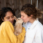 girls kissing a mini goat at The Grand Ranch near Zion National Park